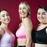 Three models laughing, looking at the camera, with sports bras on.